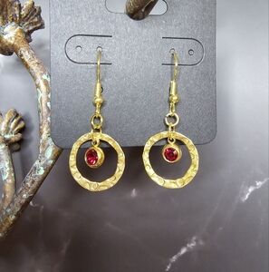 Drop earrings with red rhinestone hanging in brass embossed hollow round disc